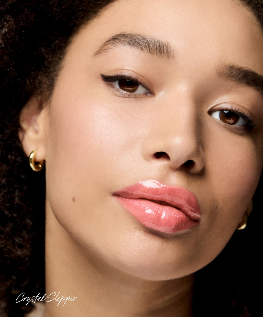 Close-up of a woman with glowing skin wearing Legendary Lip Oil in a soft pink shade, highlighting natural beauty with clean ingredients and sustainable packaging.