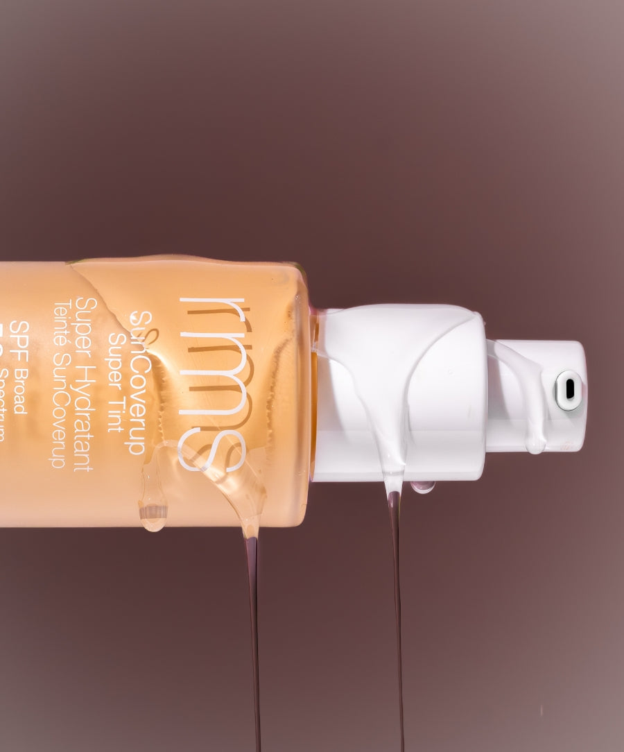 Close-up of a glass pump bottle of SunCoverup Super Tint SPF 50 with liquid foundation dripping down the side, showcasing the product’s smooth texture and tint shade.