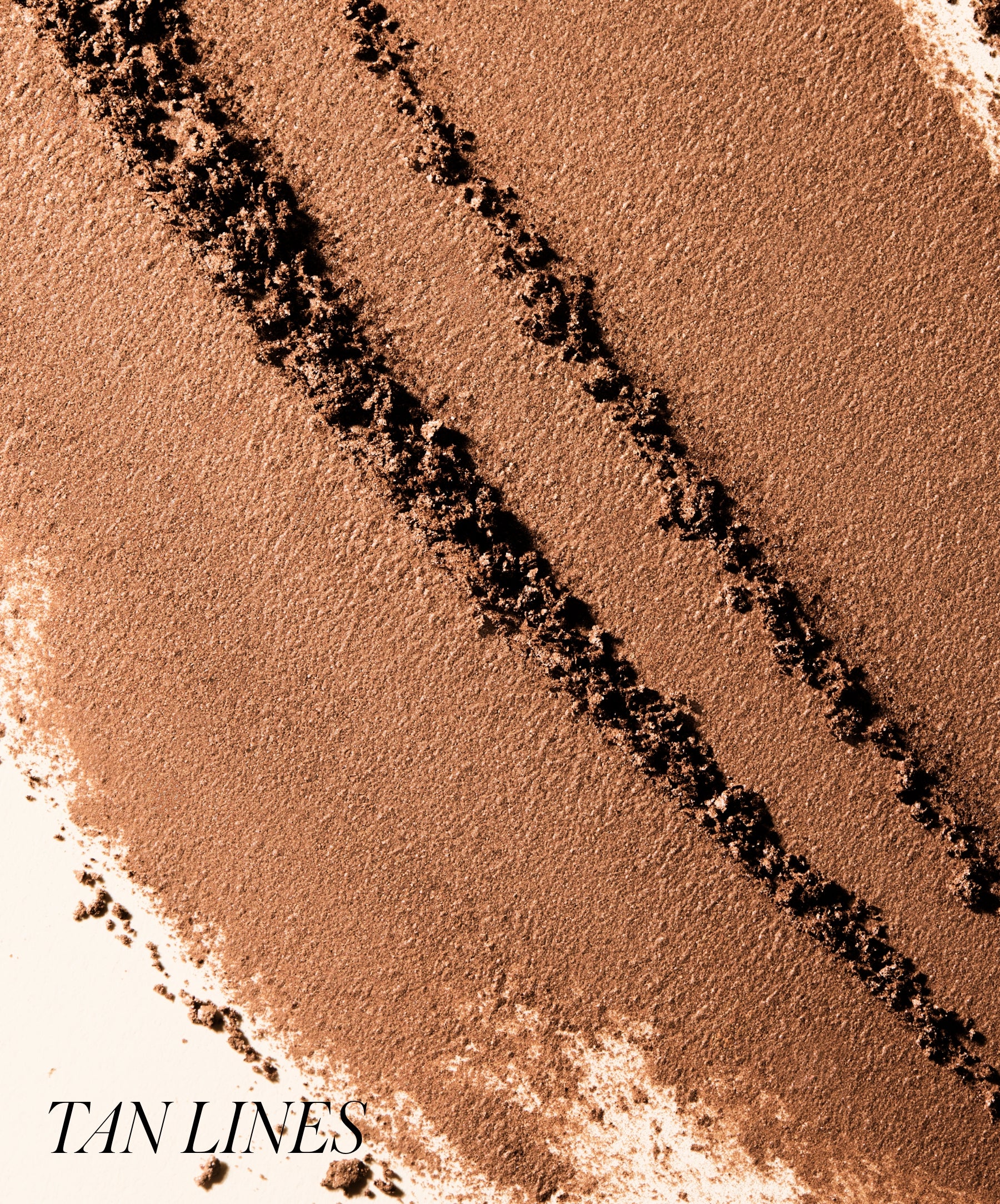 Close-up of finely milled warm tan powder with darker streaks showcasing the natural shades of ReDimension Hydra Bronzer for a smooth, clean beauty makeup look.