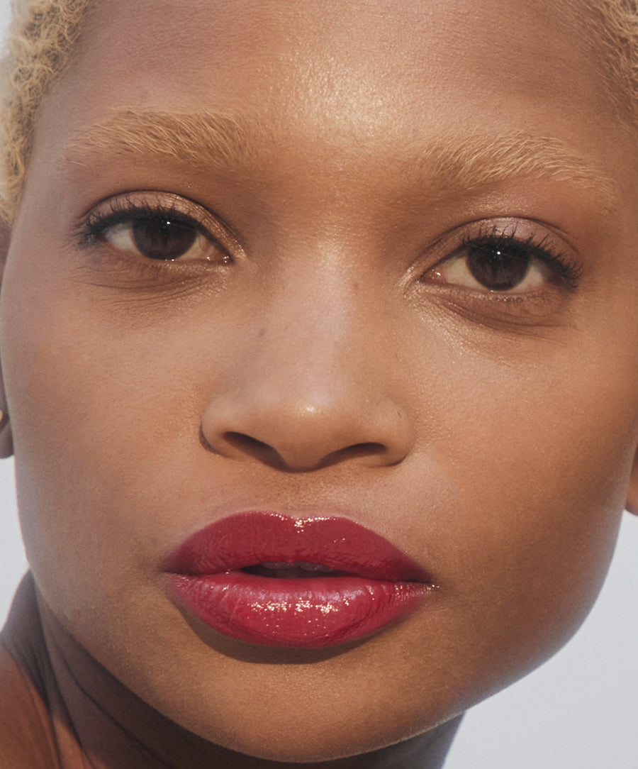 Close-up of a model wearing glossy vibrant red lips showcasing Liplights Cream Lip Gloss on smooth, natural skin with a clean beauty aesthetic.