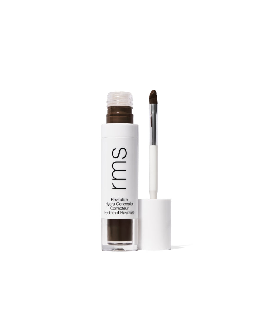 Open tube of Revitalize Hydra Concealer by RMS Beauty showing rich brown creamy product with applicator brush against white background, highlighting clean beauty and skincare infused makeup.