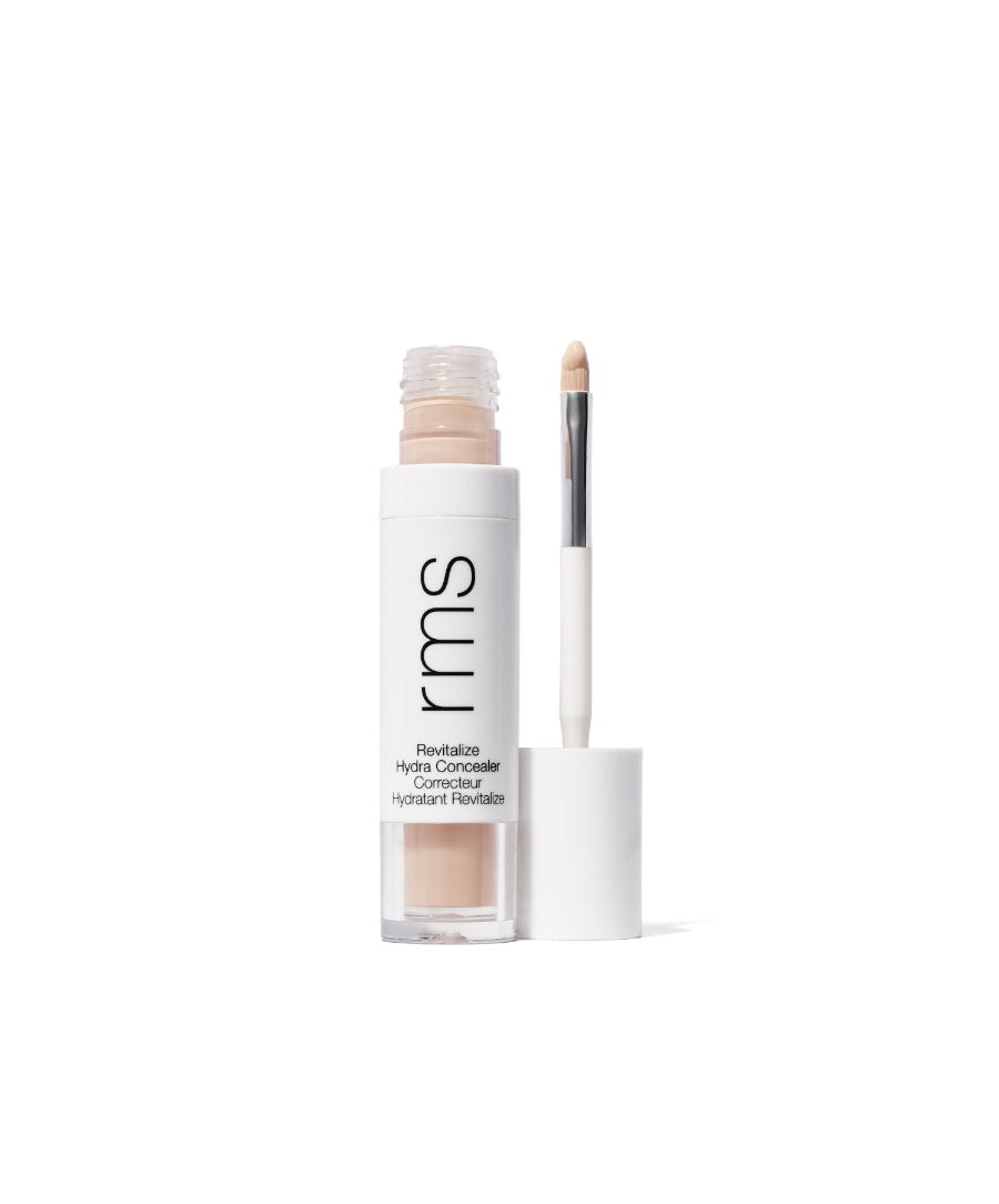 Opened tube of Revitalize Hydra Concealer with attached applicator brush showing creamy natural beige shade in sleek white and clear packaging, highlighting clean beauty makeup.