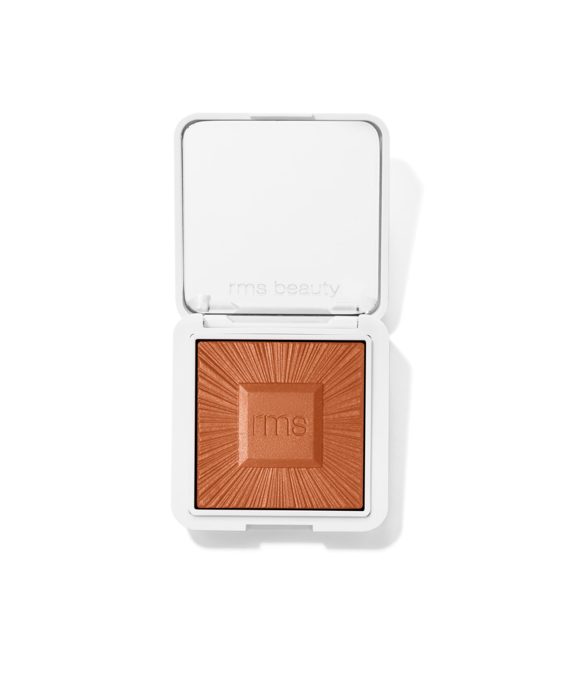 Open compact showing a warm bronze shade powder with embossed rays and the rms logo in the center, showcasing the ReDimension Hydra Bronzer in clean beauty packaging.